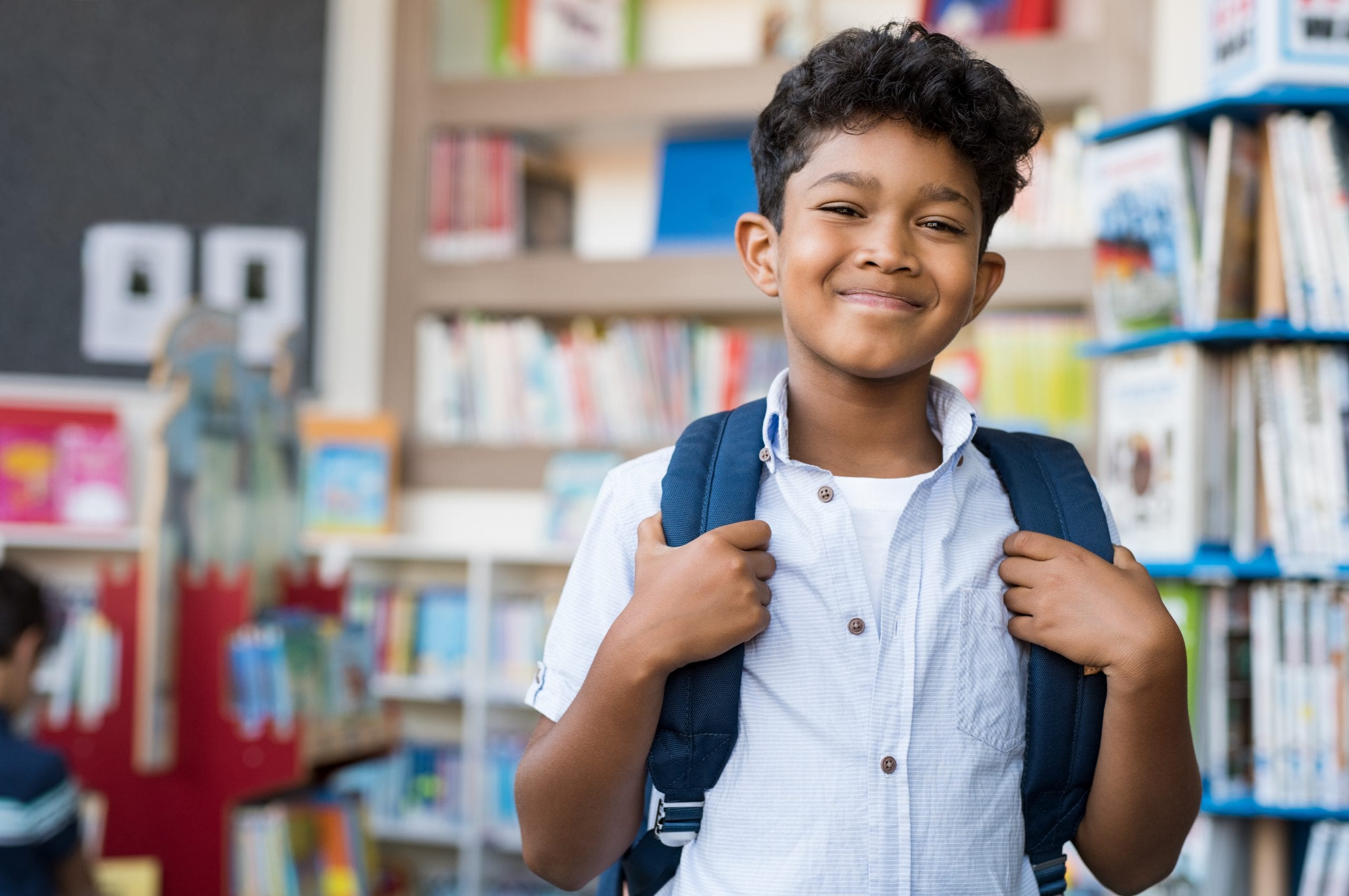 Young hispanic boy smiling with backpack on