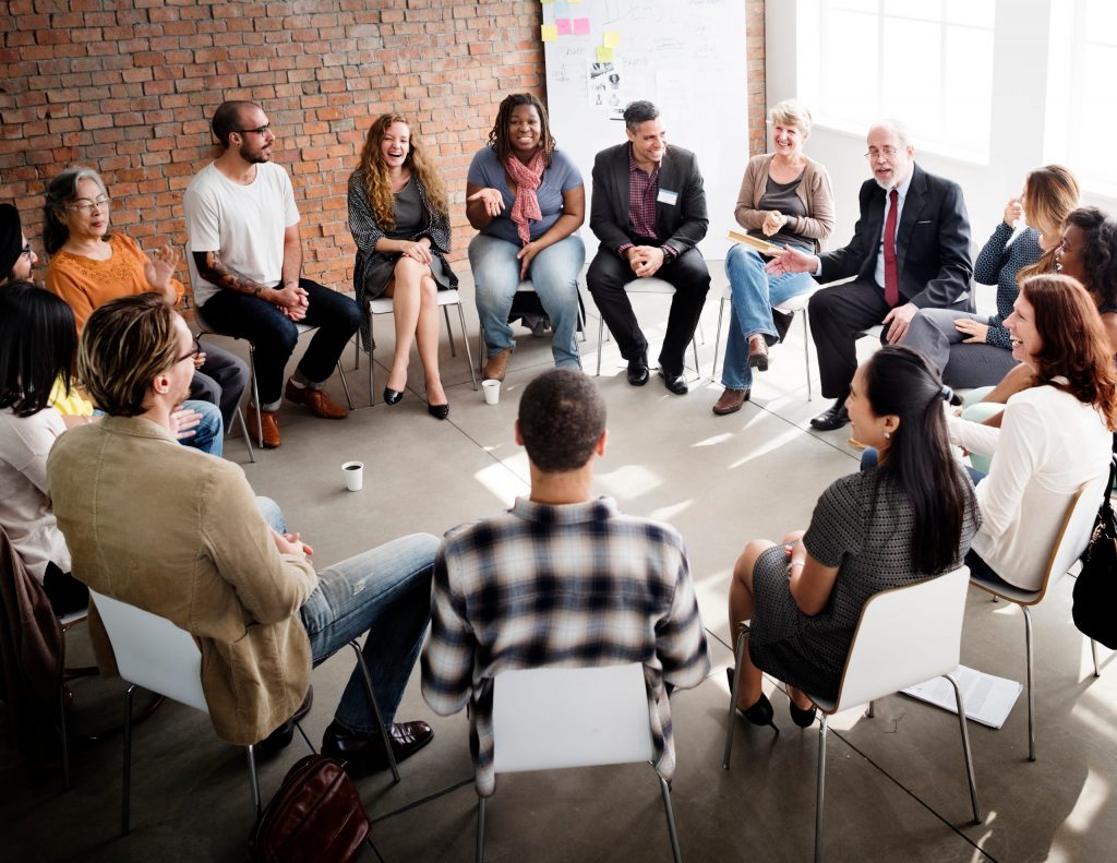 group of diverse adults sitting in chairs formed in a circle